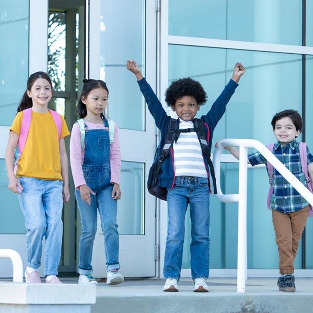 Common Questions- boy celebrates with other kids outside school