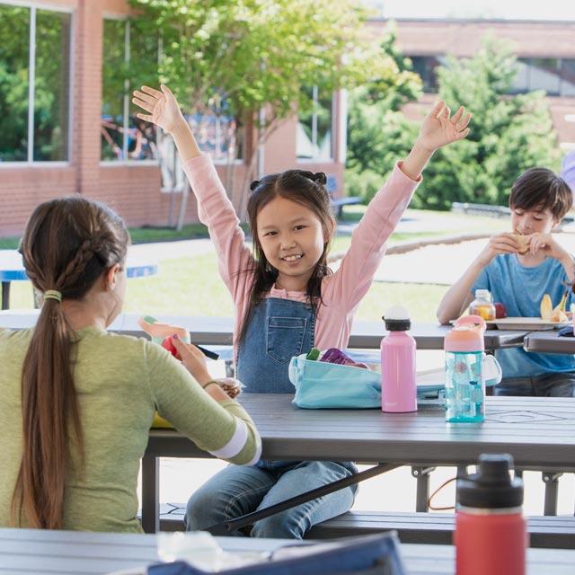 Common Questions-girl raising hands at school lunch area