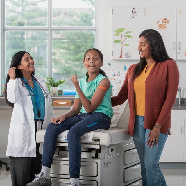 Common question-girl flexing arm with doctor and parent